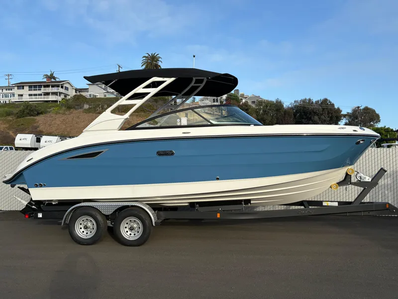 The Image of 2026 Sea Ray SDX 250 boat on trailer, blue and white design, parked outdoors. - 0