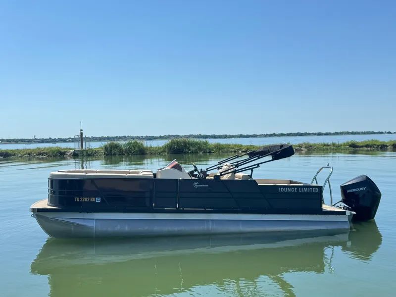The Image of 2023 Massimo Marine P24 pontoon boat on calm water, clear sky background. - 1