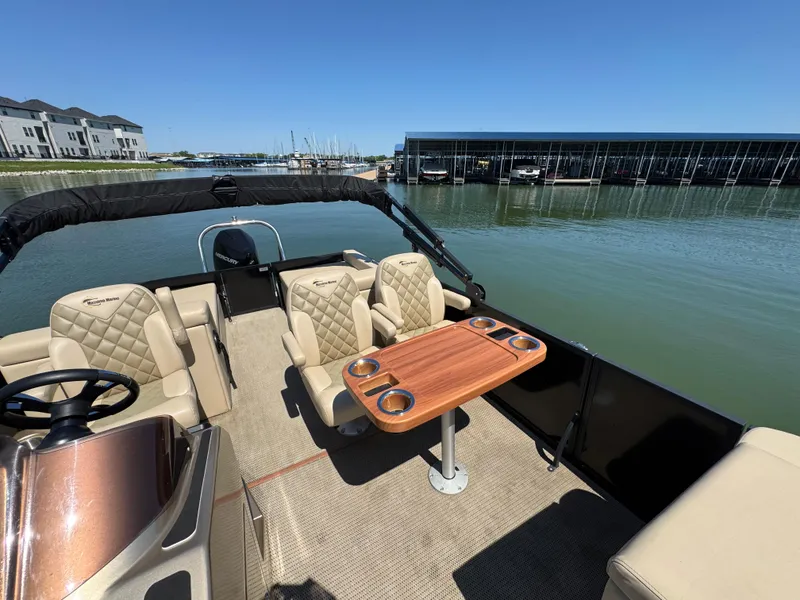 Slide: The Image of 2023 Massimo Marine P24 boat interior with seating and table on a sunny day by the marina. - 14