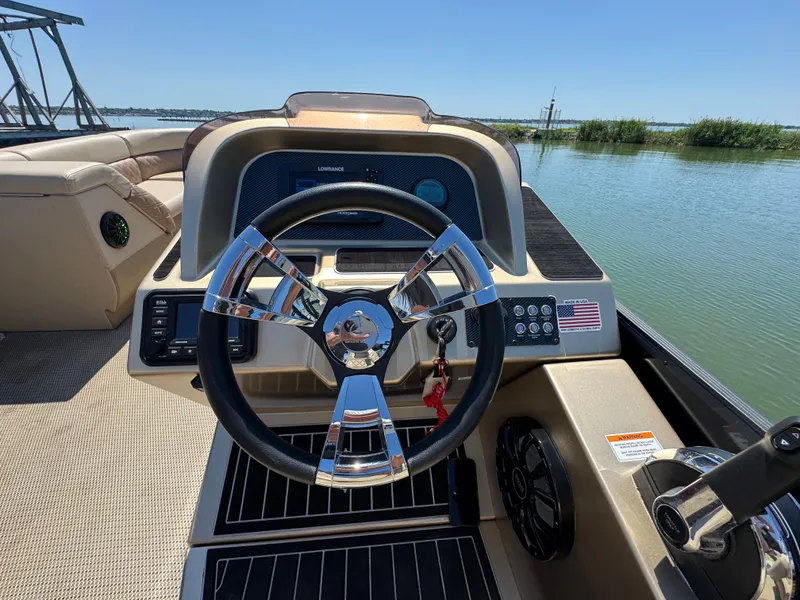 Slide: The Image of 2023 Massimo Marine P24 boat dashboard with steering wheel, overlooking calm waters. - 17
