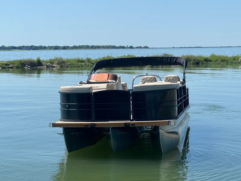 Slide: The Image of 2023 Massimo Marine P24 pontoon boat on calm lake waters. - 2