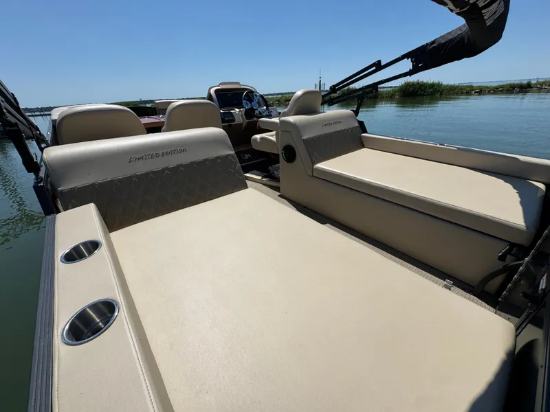 Slide: The Image of 2023 Massimo Marine P24 boat interior with beige seating and cup holders on a sunny day. - 27
