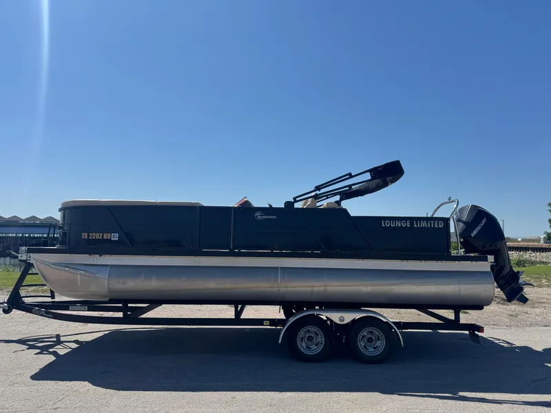 Slide: The Image of 2023 Massimo Marine P24 pontoon boat on trailer under clear blue sky. - 7