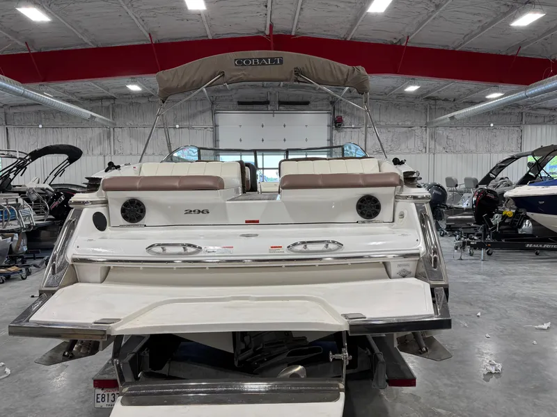 Slide: The Image of 2012 Cobalt 296 BR boat in a showroom, rear view with seating and speakers. - 5
