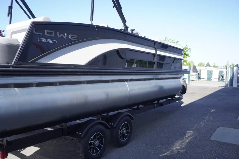 Slide: The Image of 2025 Lowe SS 230 DL pontoon boat on trailer, parked outdoors. - 11