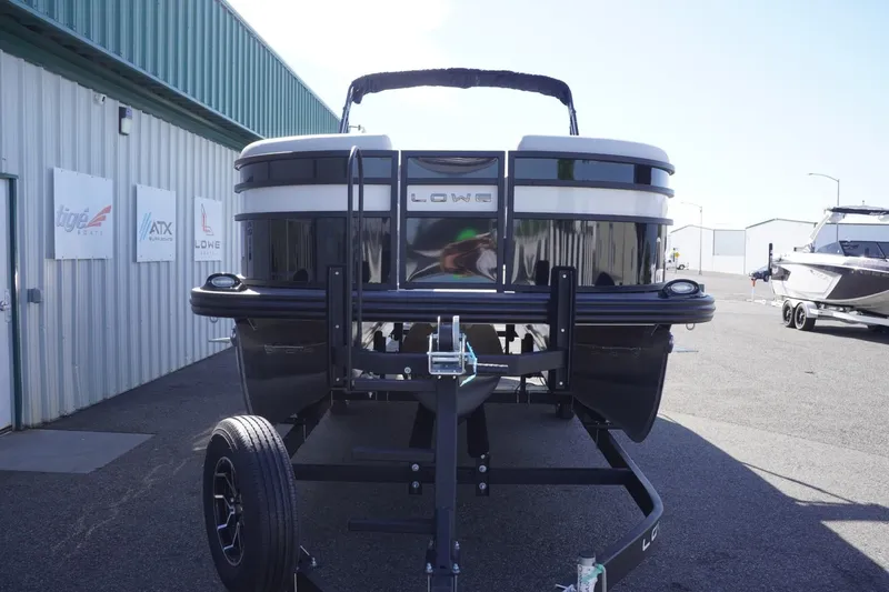 Slide: The Image of 2025 Lowe SS 230 DL pontoon boat on trailer, parked outside a building. - 16