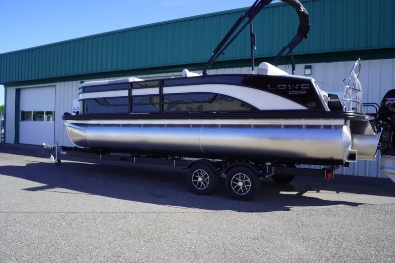 Slide: The Image of 2025 Lowe SS 230 DL pontoon boat on trailer, parked outside a green building. - 3