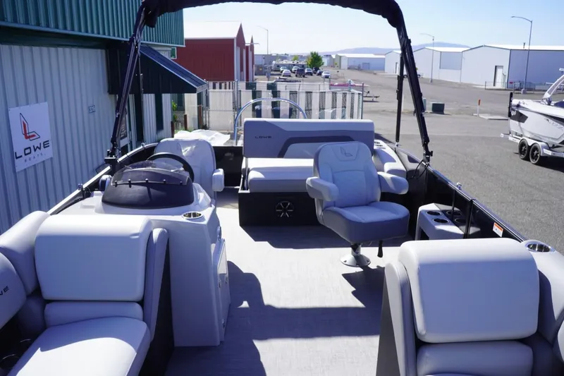 Slide: The Image of 2025 Lowe SS 230 DL pontoon boat interior with seating and helm, docked at marina. - 39