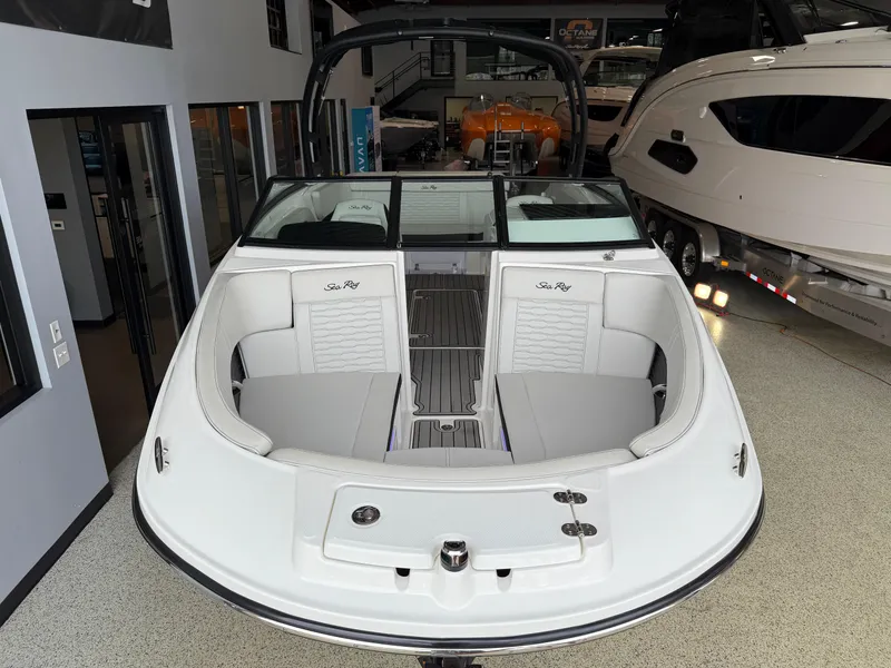 Slide: The Image of 2024 Sea Ray SPX230 boat interior, featuring spacious seating and modern design in a showroom. - 11