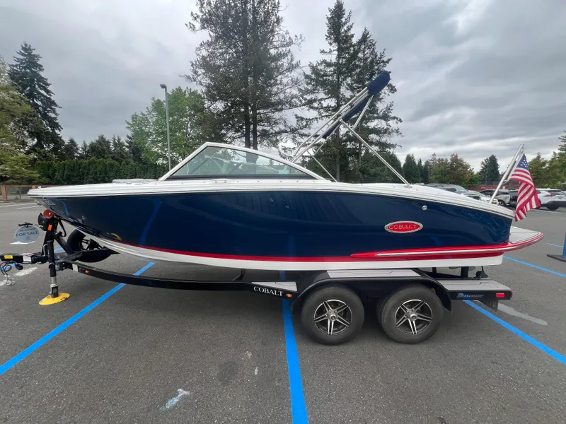 Slide: The Image of 2023 Cobalt CS22 boat on trailer, parked in lot with American flag. - 5