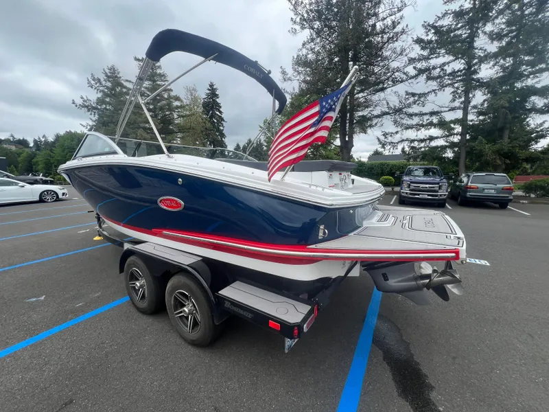 Slide: The Image of 2023 Cobalt CS22 boat on trailer with American flag, parked in lot. - 6