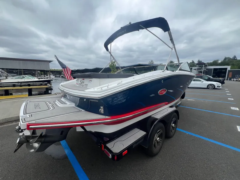 Slide: The Image of 2023 Cobalt CS22 boat on trailer, dockside, with American flag, overcast sky. - 8