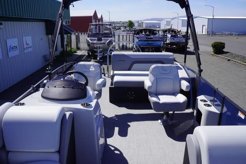 Slide: The Image of 2025 Lowe SS 230 DL pontoon boat with modern seating and steering console, docked outdoors. - 24