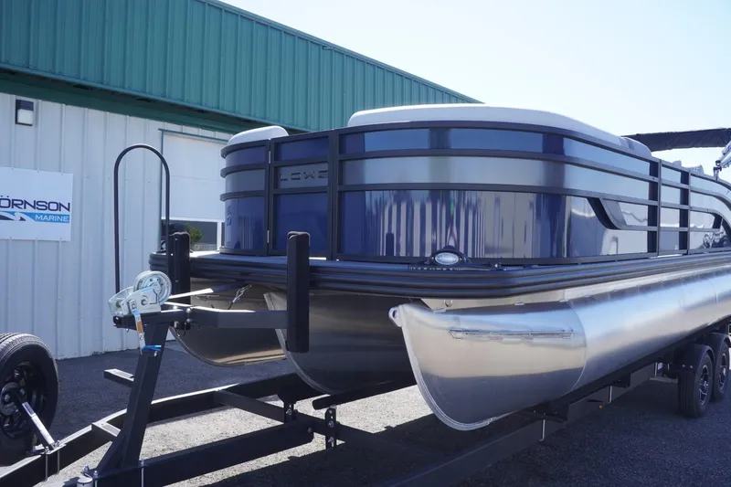 Slide: The Image of 2025 Lowe SS 230 DL pontoon boat on trailer, parked outside a marine building. - 3