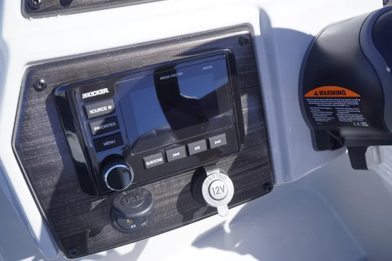 Slide: The Image of Control panel of 2025 Lowe SS 230 DL boat featuring Kicker audio system and 12V outlet. - 41