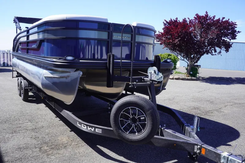 Slide: The Image of 2025 Lowe SS 230 DL pontoon boat on trailer, parked outdoors. - 5