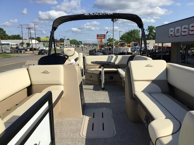 Slide: The Image of 2025 G3 Select 322RF pontoon boat with beige seating and canopy, parked near dealership. - 19