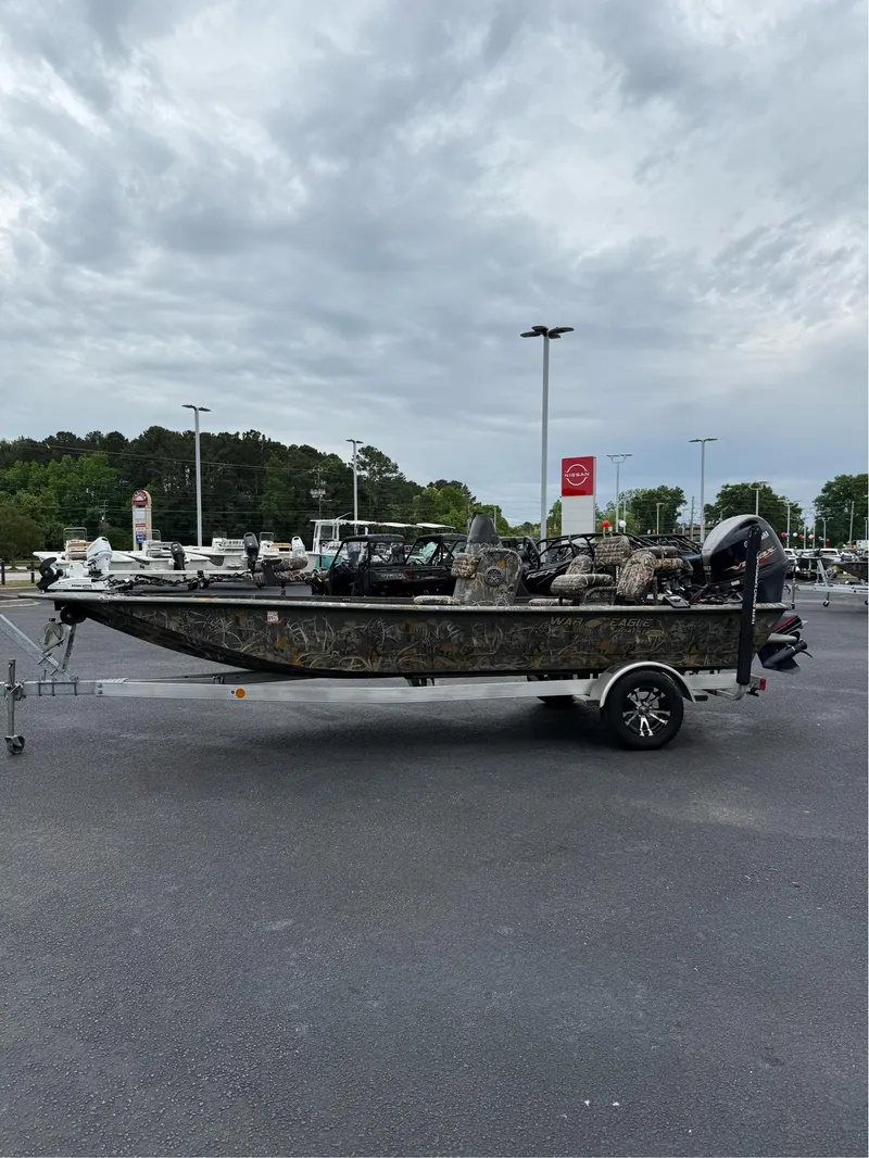 Slide: The Image of 2022 War Eagle 961 Blackhawk boat on trailer in parking lot under cloudy sky. - 15
