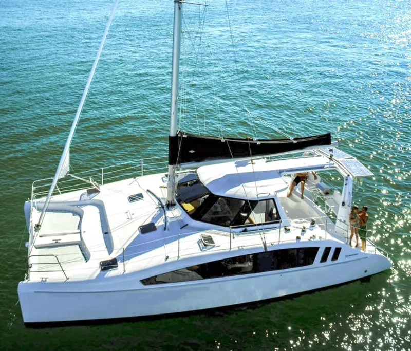 Slide: The Image of 2025 Seawind 1160 Lite catamaran sailing on clear blue water. - 0