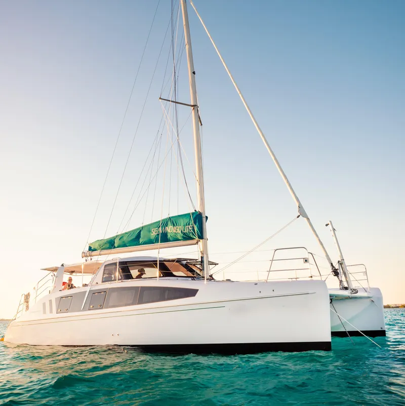 Slide: The Image of 2025 Seawind 1160 Lite catamaran sailing on clear blue water under a sunny sky. - 2