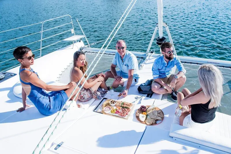 Slide: The Image of Group enjoying a meal on a 2025 Seawind 1160 Lite catamaran deck. - 7