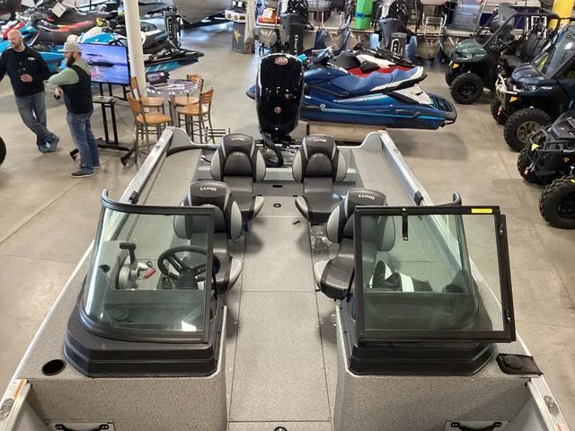 Slide: The Image of 2024 Lund 2075 Alaskan Sport boat interior in showroom, featuring seating and steering console. - 6