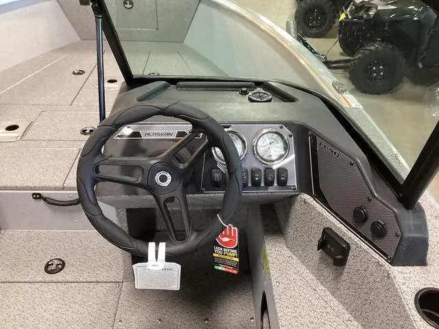 Slide: The Image of 2024 Lund 2075 Alaskan Sport boat dashboard with steering wheel and gauges. - 9