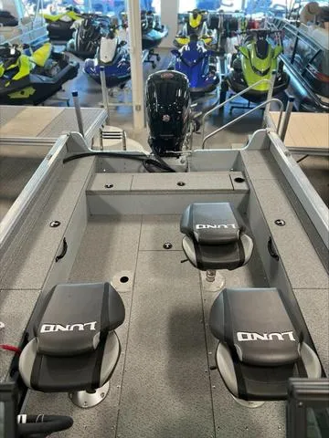 Slide: The Image of 2024 Lund 1875 Alaskan DC boat interior with seating and motor, displayed in showroom. - 10