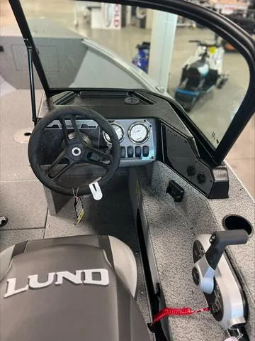 Slide: The Image of 2024 Lund 1875 Alaskan DC boat interior with steering wheel and control panel. - 12