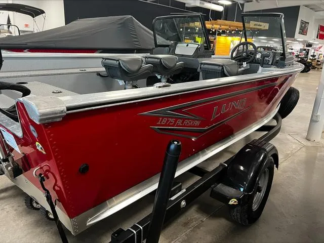 Slide: The Image of 2024 Lund 1875 Alaskan DC boat in showroom, red exterior, on trailer. - 23