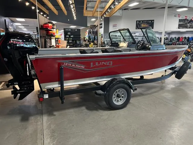 Slide: The Image of 2024 Lund 1875 Alaskan DC boat in showroom, red exterior, on trailer. - 4