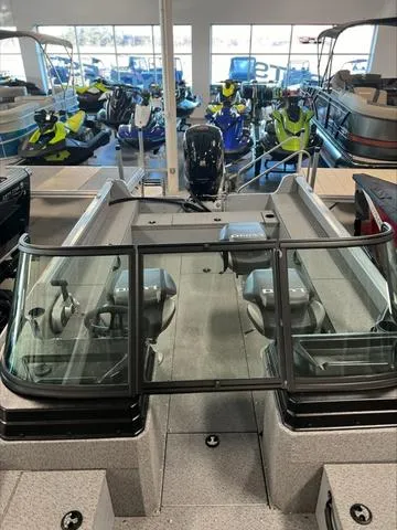 Slide: The Image of 2024 Lund 1875 Alaskan DC boat in showroom, surrounded by various watercraft. - 9