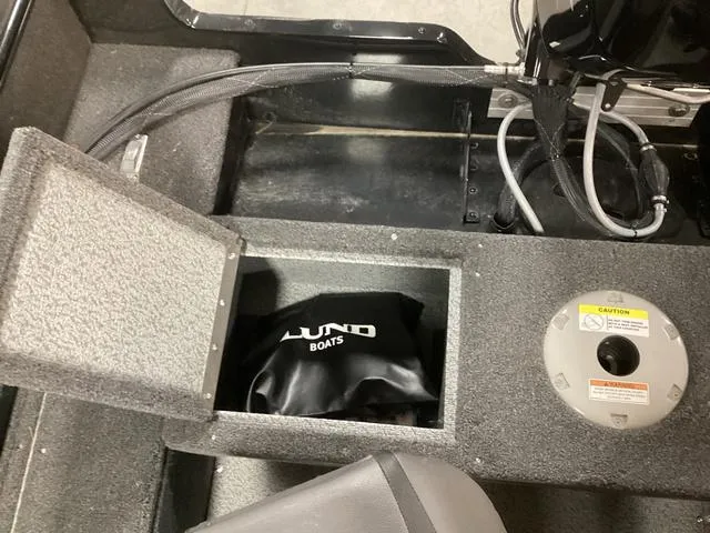 Slide: The Image of 2024 Lund 1650 Rebel XL SS boat storage compartment with Lund bag and caution label. - 5