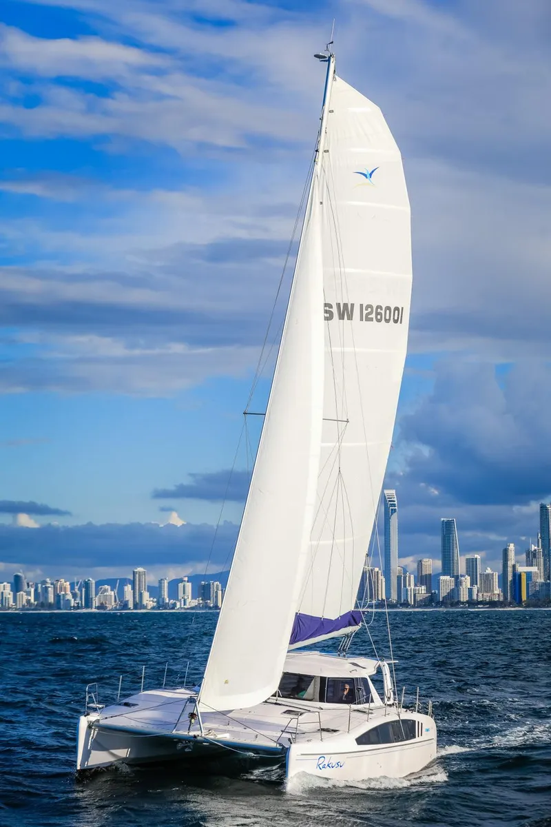 Slide: The Image of 2025 Seawind 1260 catamaran sailing near city skyline under clear skies. - 1
