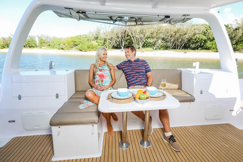 Slide: The Image of Couple relaxing on Seawind 1260 catamaran, enjoying a meal with a scenic beach backdrop. - 13