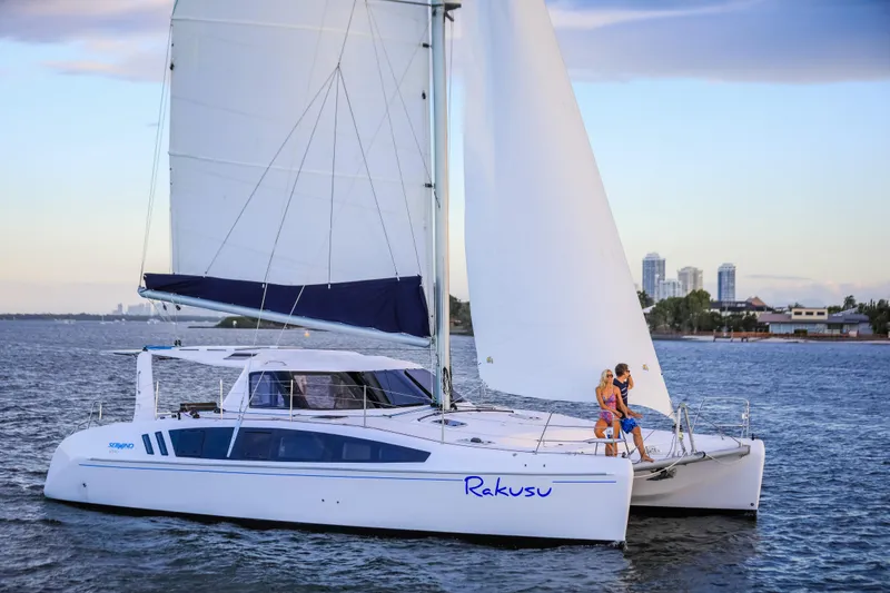 Slide: The Image of 2025 Seawind 1260 catamaran sailing on calm waters with two people on deck. - 2