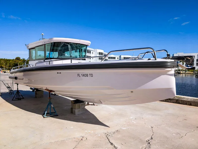 Slide: The Image of 2022 Axopar 28 CABIN boat on stands, dockside, under clear blue sky. - 1