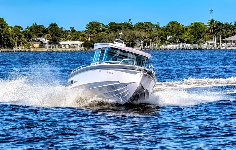 Slide: The Image of 2022 Axopar 28 CABIN boat cruising on a sunny day, creating waves. - 2