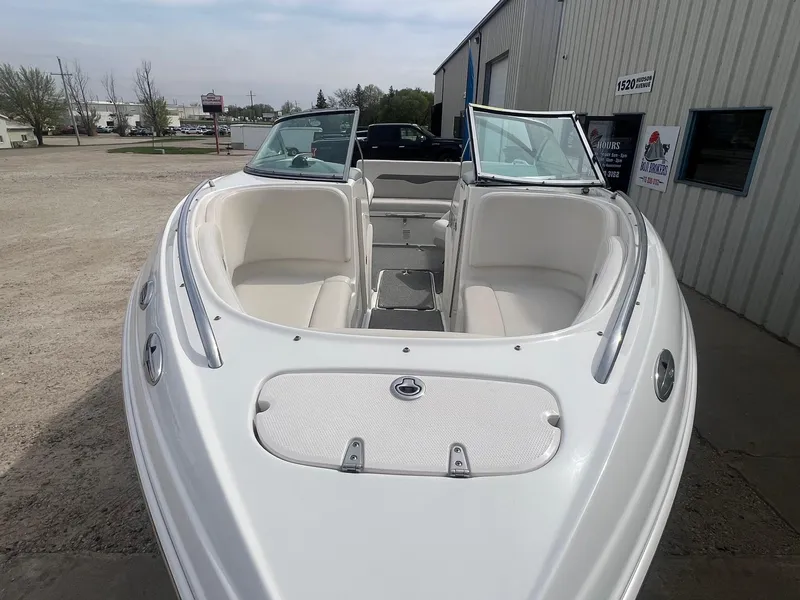 Slide: The Image of 2008 Chaparral 220 SSi boat with open bow seating, parked near a building. - 5