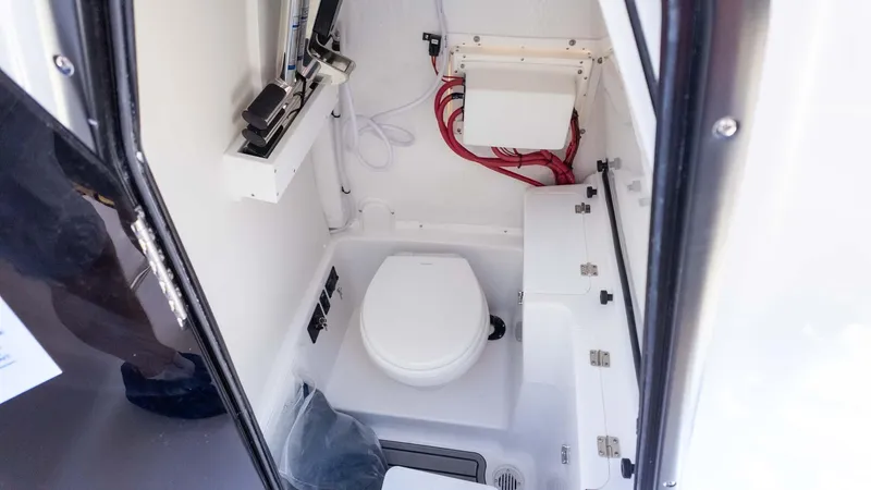 Slide: The Image of 2025 Tidewater 272cc boat interior with compact marine toilet and storage. - 27