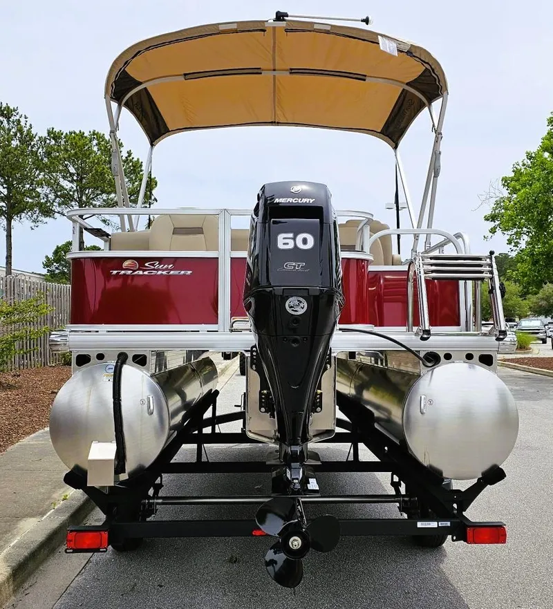 Slide: The Image of 2025 Sun Tracker Bass Buggy 18 DLX pontoon boat with Mercury 60 engine, parked on a street. - 3