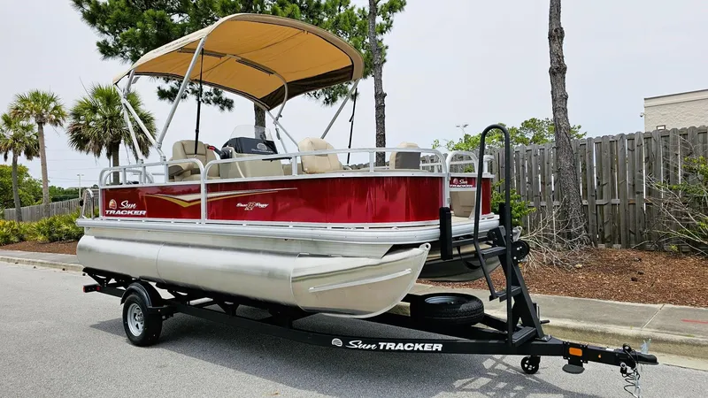 Slide: The Image of 2025 Sun Tracker Bass Buggy 18 DLX pontoon boat on trailer, red and beige design. - 4