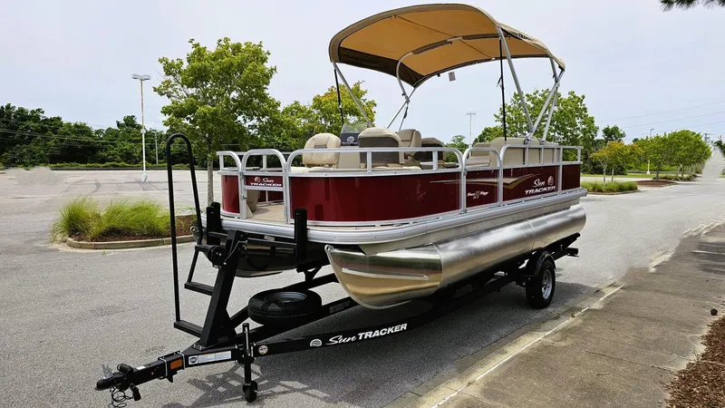Slide: The Image of 2025 Sun Tracker Bass Buggy 18 DLX pontoon boat on trailer in parking lot. - 6