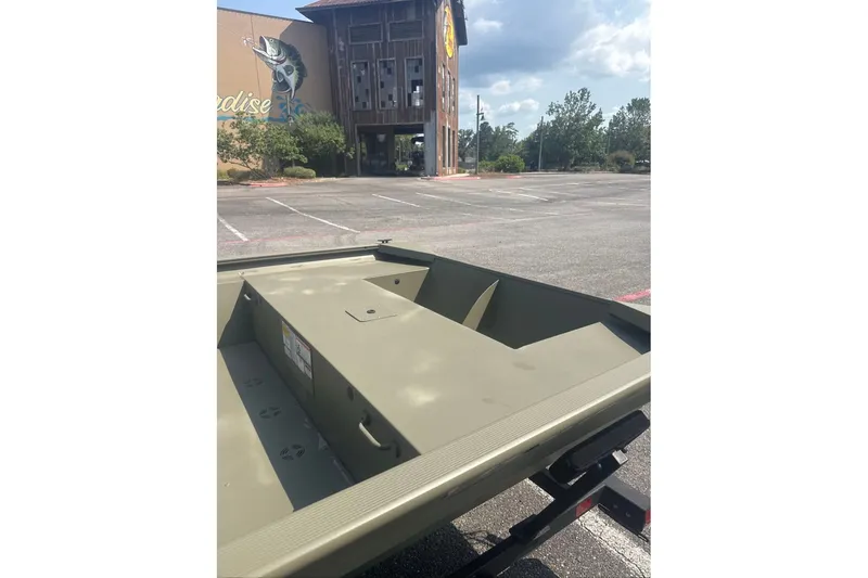 Slide: The Image of 2025 Tracker Grizzly 1860 Utility boat in parking lot, near a building with fish mural. - 4