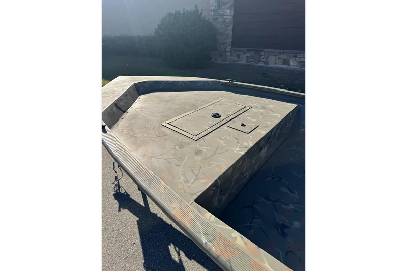 Slide: The Image of 2025 Tracker Grizzly 1648 Jon boat with camouflage deck, parked outdoors. - 6