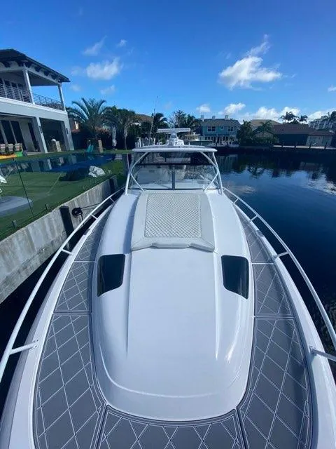 Slide: The Image of 2019 Intrepid 475 Sport Yacht docked by waterfront homes under blue sky. - 27