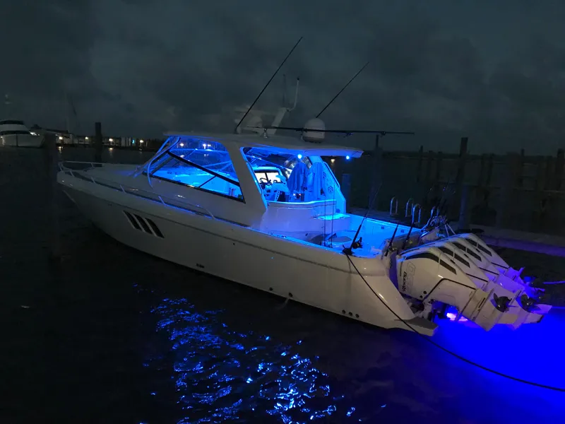 Slide: The Image of 2019 Intrepid 475 Sport Yacht illuminated with blue lights at night. - 3