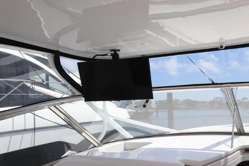 Slide: The Image of 2019 Intrepid 475 Sport Yacht interior with mounted TV and marina view. - 32