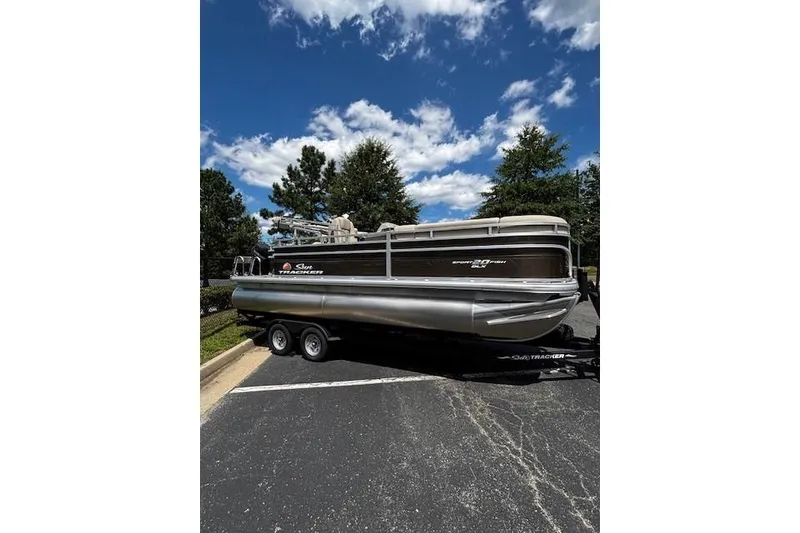 The Image of 2025 Sun Tracker SportFish 20 DLX pontoon boat on trailer, parked outdoors. - 0