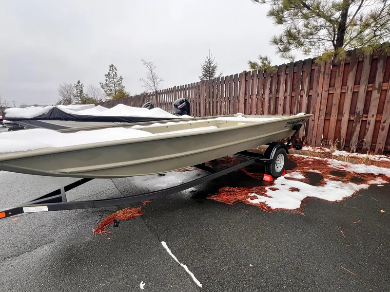 Slide: The Image of 2025 Tracker GRIZZLY 1860 Utility boat on trailer, snowy day, wooden fence background. - 2
